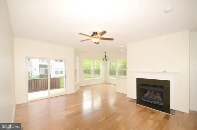 an empty room with fireplace fan and windows