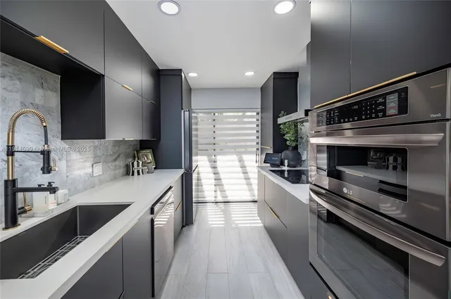 a large kitchen with stainless steel appliances a large counter top a stove and a sink