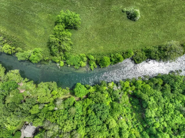 an aerial view of residential house with outdoor space and trees all around