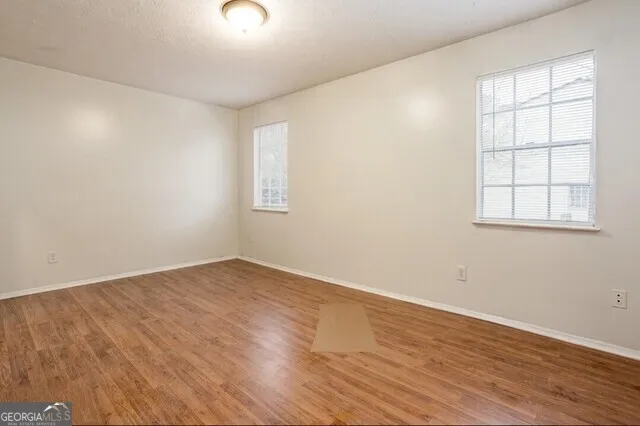an empty room with wooden floor and windows