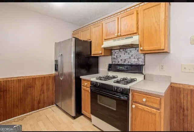 a kitchen with stainless steel appliances granite countertop a stove a refrigerator and a sink