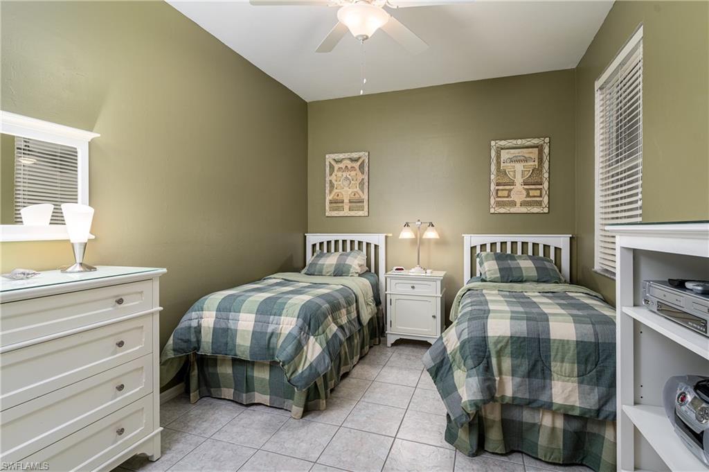 1927 Morning Sun Lane, Unit F27 Naples, FL 34119 - Photo 14 of 17 a bedroom with two beds and a chandelier