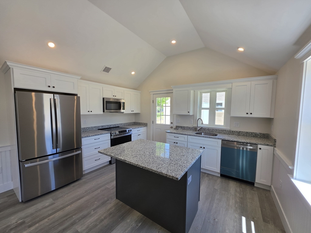 87 Acapesket Road, Unit 2B Falmouth, MA 02536 - Photo 2 of 17 a kitchen with a center island wooden floor and stainless steel appliances