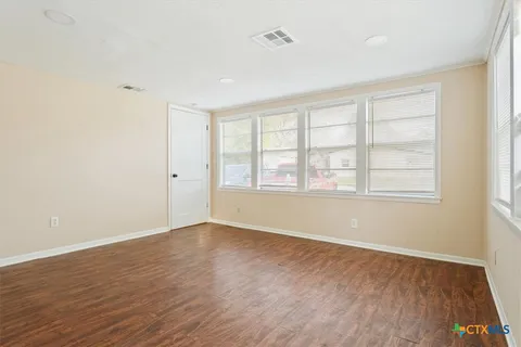 an empty room with wooden floor and windows
