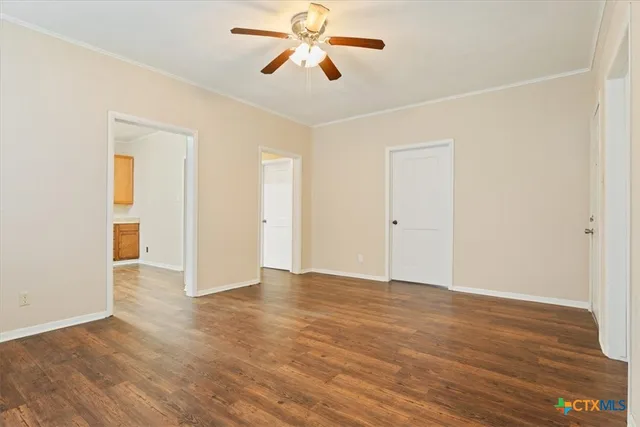 an empty room with wooden floor and ceiling fan