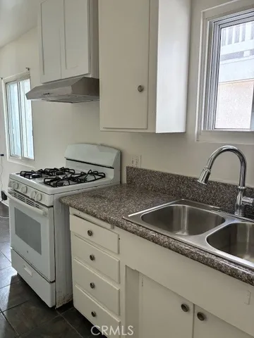 a kitchen with granite countertop white cabinets sink and appliances