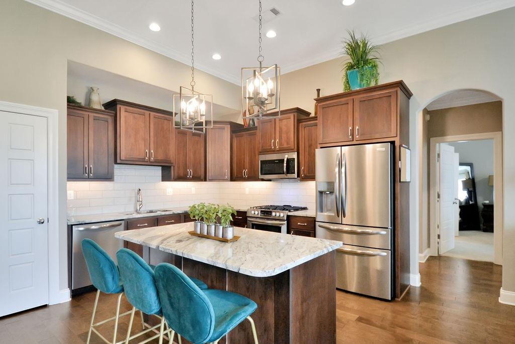 70 Trinity Cove Atoka, TN 38004 - Photo 4 of 20 a kitchen with stainless steel appliances granite countertop a refrigerator a sink a stove a dining table and chairs