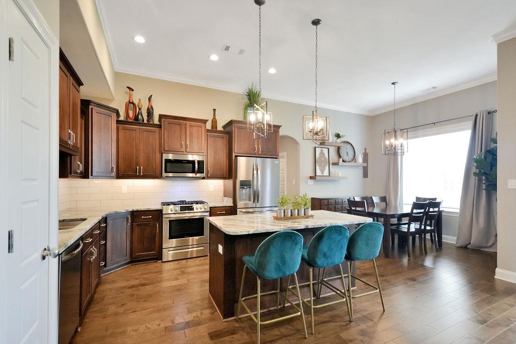 70 Trinity Cove Atoka, TN 38004 - Photo 5 of 20 a kitchen with stainless steel appliances granite countertop a stove top oven a sink dishwasher a dining table and chairs with wooden floor