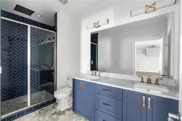a bathroom with a granite countertop sink a toilet a mirror and shower