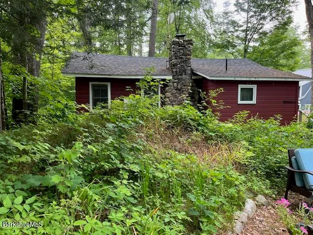 a view of a brick house with a small yard plants and large tree
