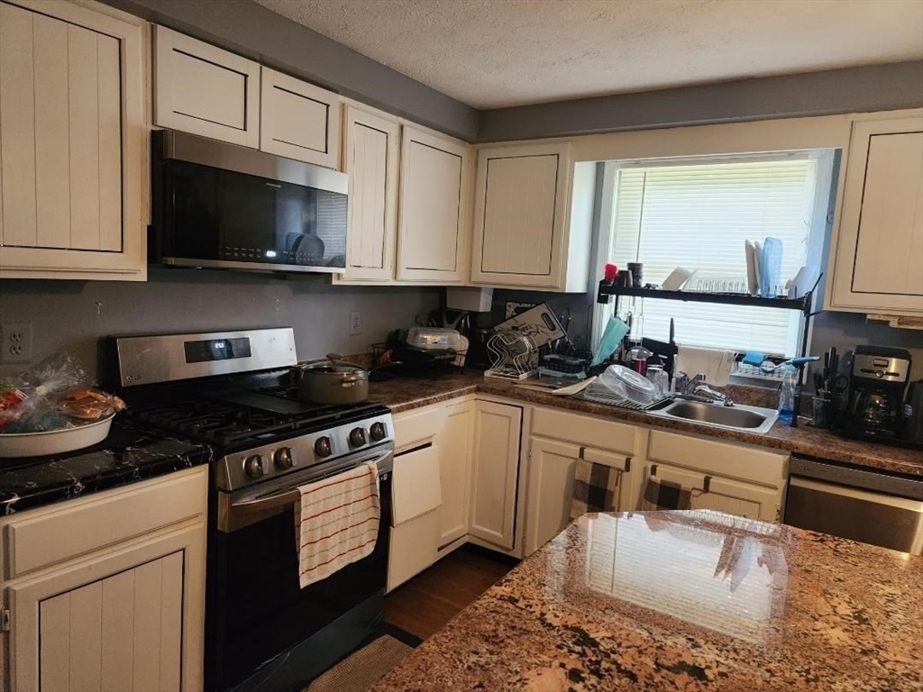 21 Brattle Street Worcester, MA 01606 - Photo 9 of 14 a kitchen with stainless steel appliances granite countertop a sink a stove a microwave and cabinets