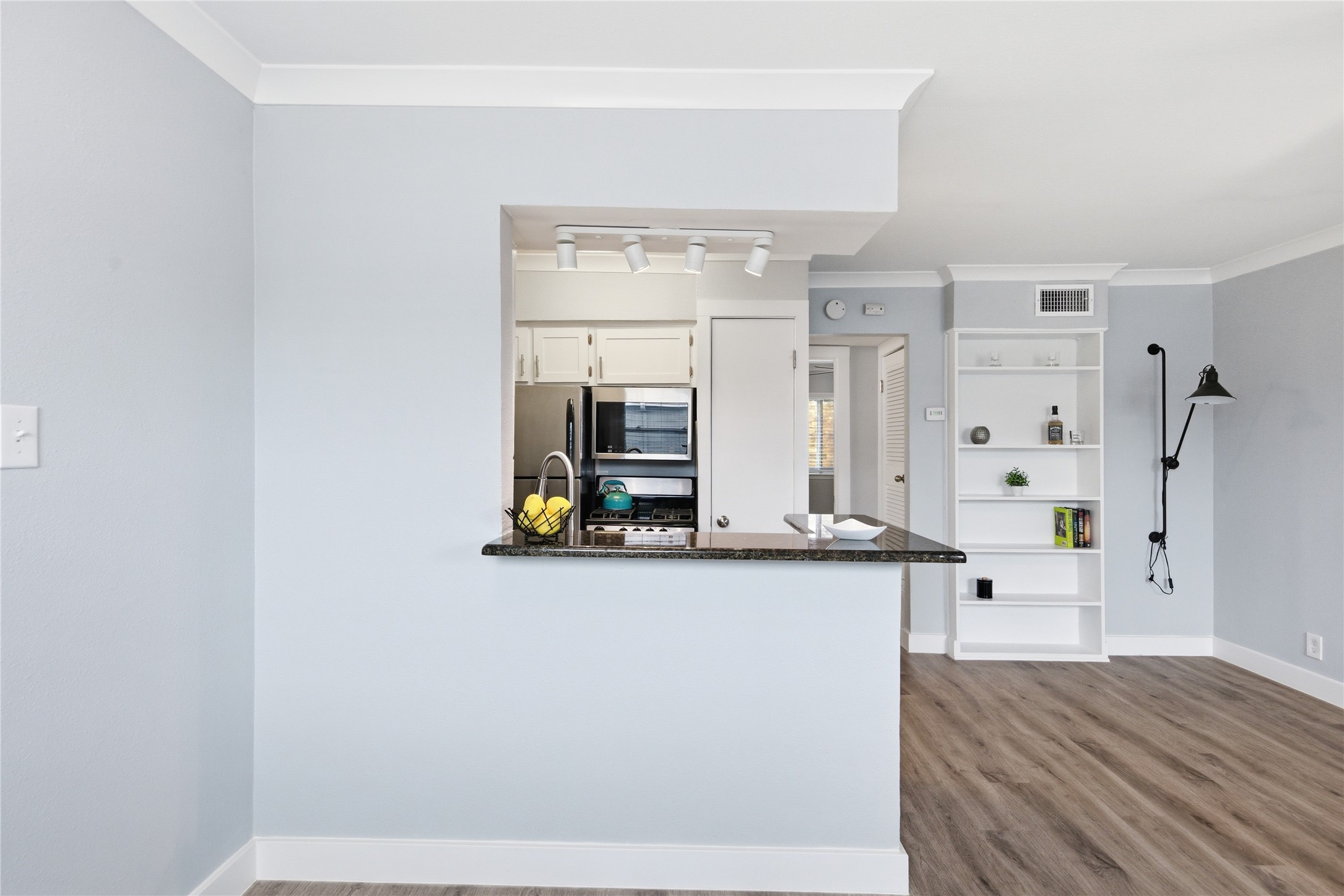 2401 Manor Road, Unit 232 Austin, TX 78722 - Photo 5 of 32 Kitchen with white cabinetry, ornamental molding, dark granite counters, and a breakfast bar