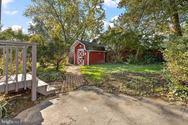 a sign that is sitting in front of a brick house with large windows