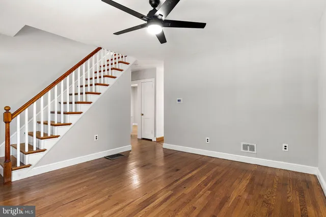 a view of an empty room with wooden floor and stairs