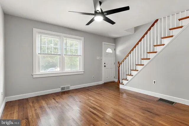a view of empty room with wooden floor and fan