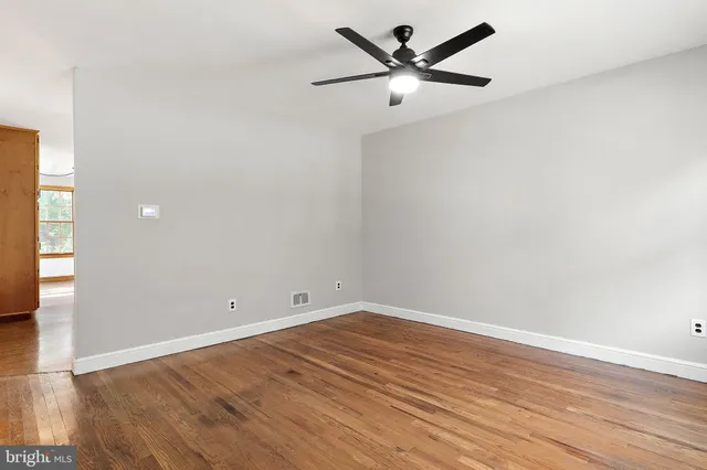 an empty room with wooden floor and a ceiling fan