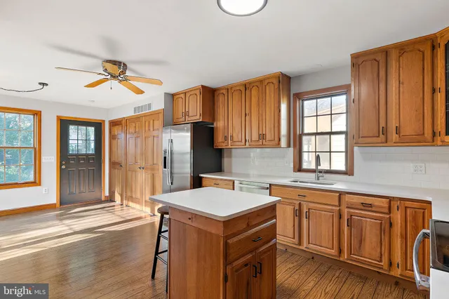 a kitchen with a stove a sink dishwasher and a dining table with wooden floor
