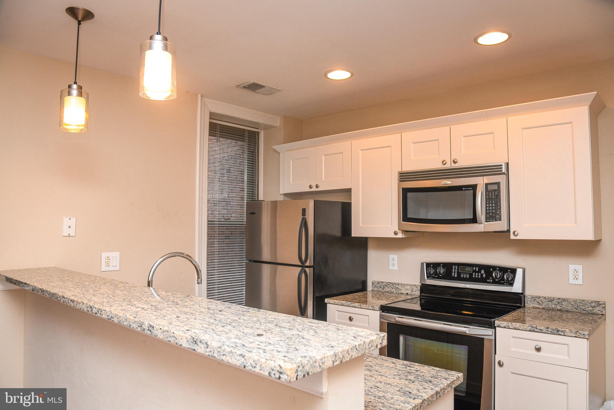 1811-19 Chestnut Street, Unit 404 Philadelphia, PA 19103 - Photo 5 of 17 a kitchen with kitchen island granite countertop a stove a sink and a refrigerator