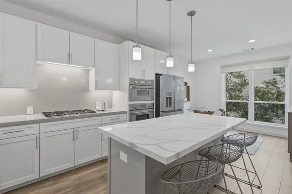 a kitchen with a stove a refrigerator a sink and white cabinets with wooden floor