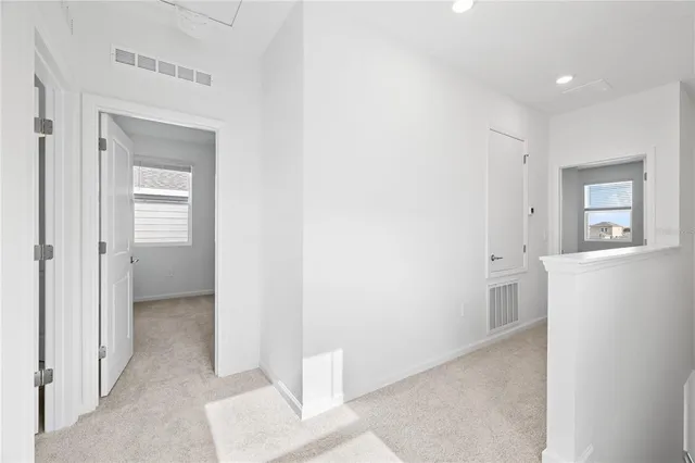 a view of a hallway with bathroom and wooden floor