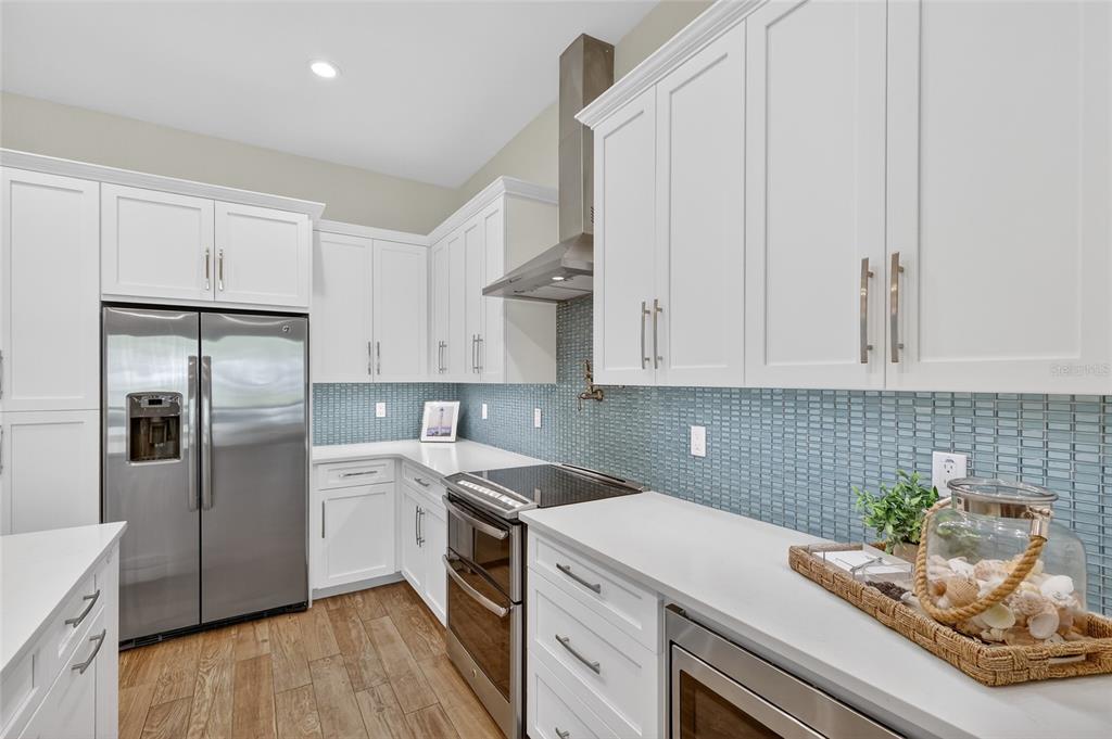 261 Seabreeze Court Boca Grande, FL 33921 - Photo 9 of 44 a kitchen with stainless steel appliances white cabinets and wooden floor