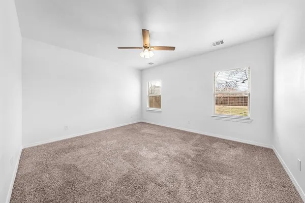 en empty room with windows and ceiling fan