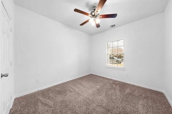 an empty room with a window and a fan