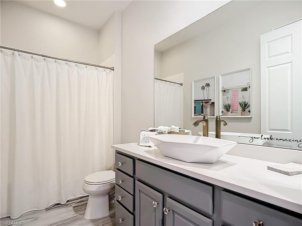 4752 Stratford Court, Unit 1404 Naples, FL 34105 - Photo 19 of 34 a bathroom with a sink a toilet and a mirror
