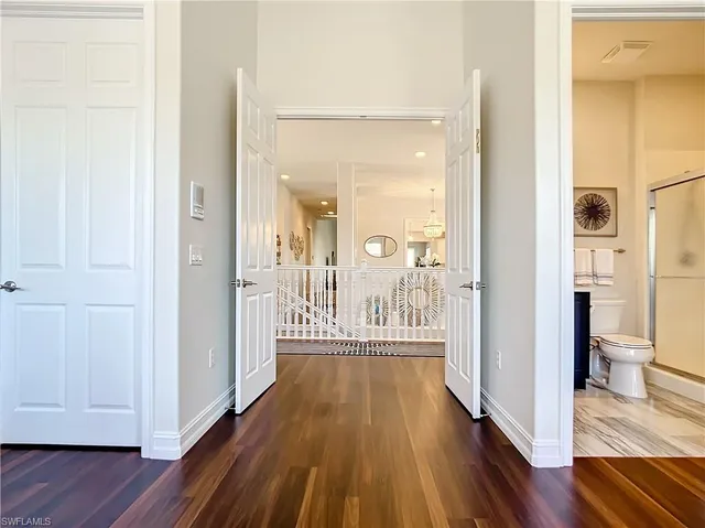 a view of a hallway with wooden floor and a bathroom