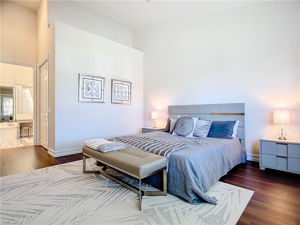 4752 Stratford Court, Unit 1404 Naples, FL 34105 - Photo 26 of 34 a spacious bedroom with a bed and wooden floor