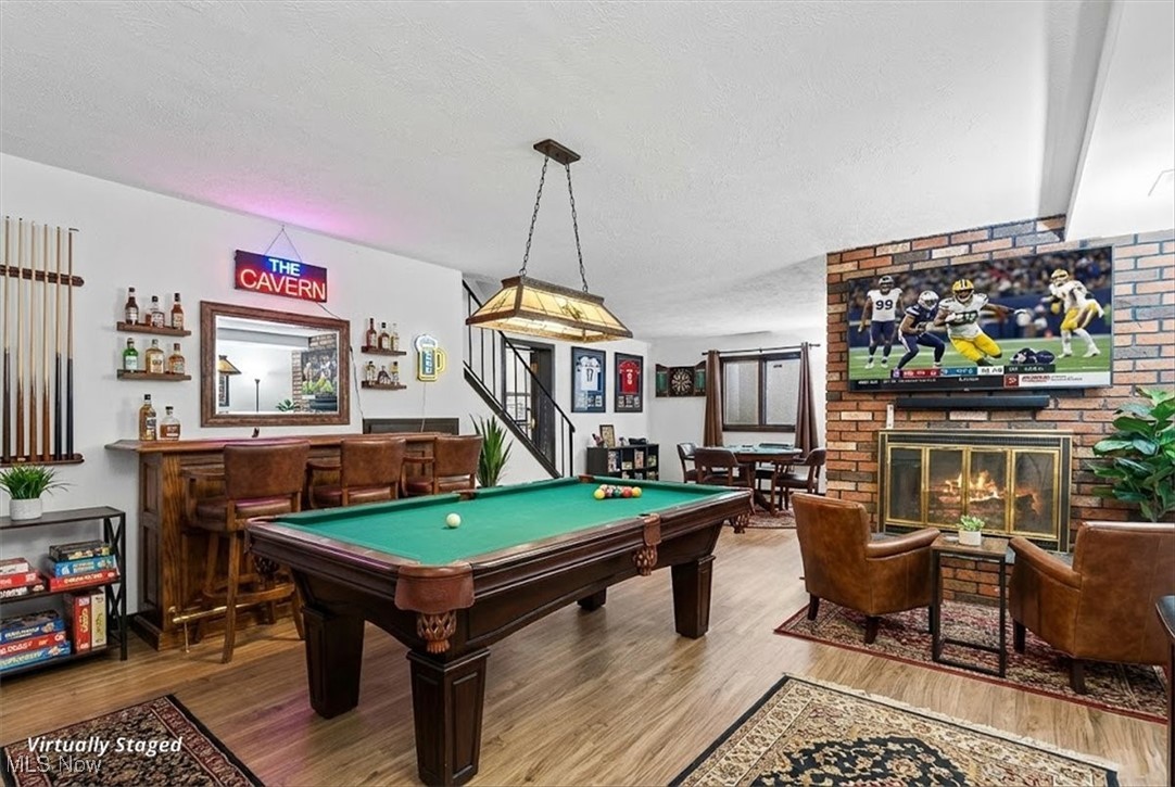 3863 Sourek Rd Extension Akron, OH 44333 - Photo 31 of 42 Rec room featuring a bar, wood finished floors, a textured ceiling, a brick fireplace, and pool table
