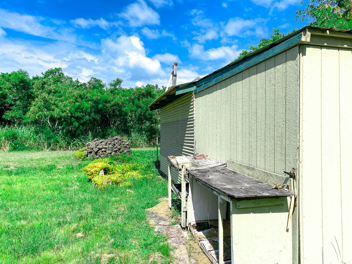 94-1488 Kala Place Naalehu, HI 96772 - Photo 11 of 19 a backyard of a house with table and chairs under an umbrella