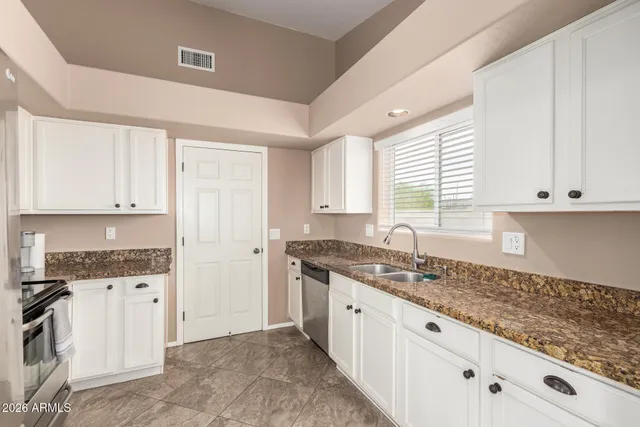a kitchen with granite countertop white cabinets and white appliances