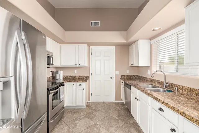 a kitchen with granite countertop a refrigerator stove top oven and sink