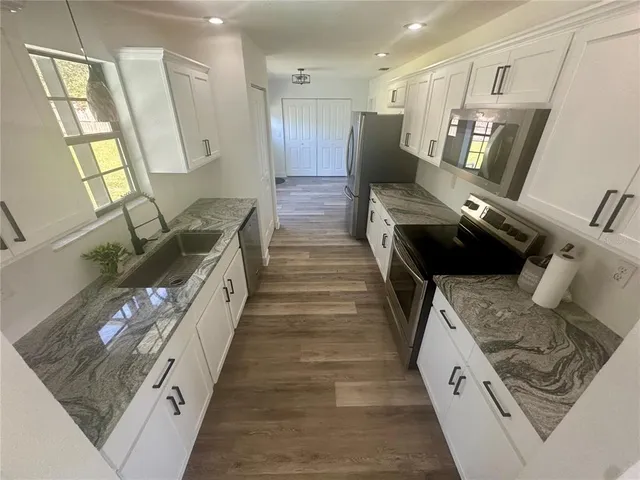 a kitchen with stainless steel appliances granite countertop a stove a microwave and a sink