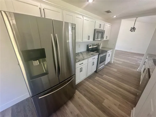 a kitchen with granite countertop white cabinets and a window