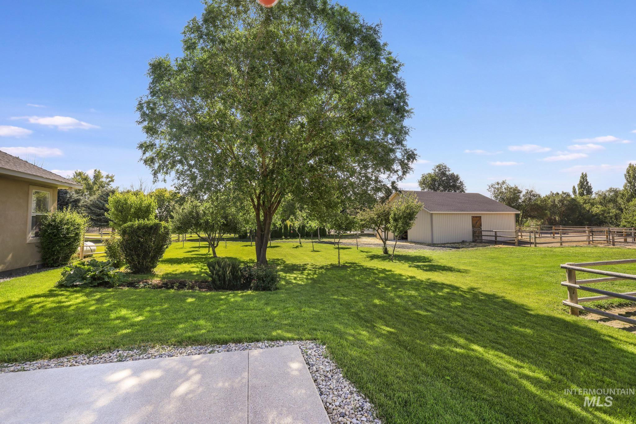 1301 Kanaka Rapids Road Buhl, ID 83316 - Photo 42 of 50 Expansive outdoor space featuring a large concrete patio with pebble accents, a mature tree providing natural shade, and manicured lawns