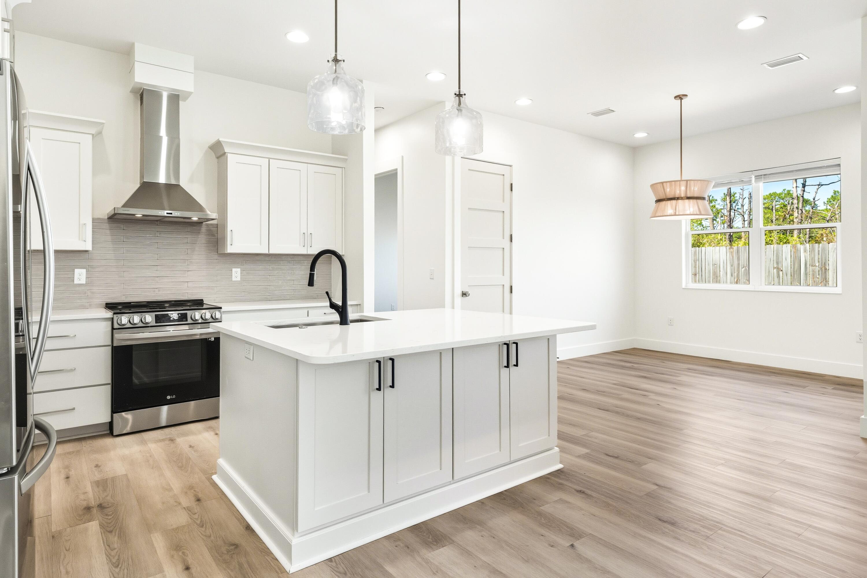 219 Loral Road Santa Rosa Beach, FL 32459 - Photo 11 of 26 a kitchen with stainless steel appliances a sink stove and wooden floor
