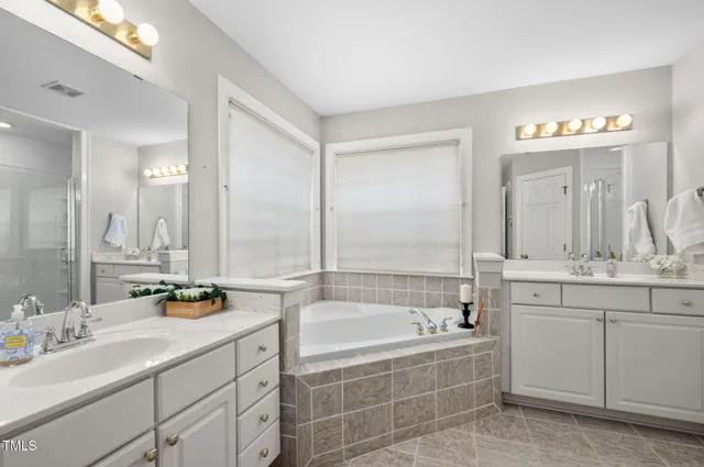 a bathroom with a bathtub a double vanity sink and mirror