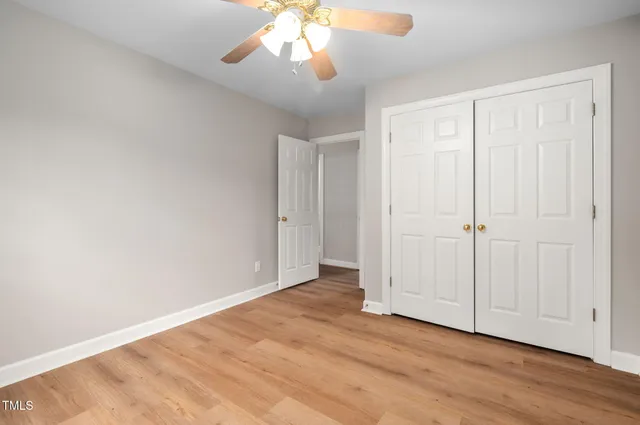 an empty room with wooden floor chandelier and closet area
