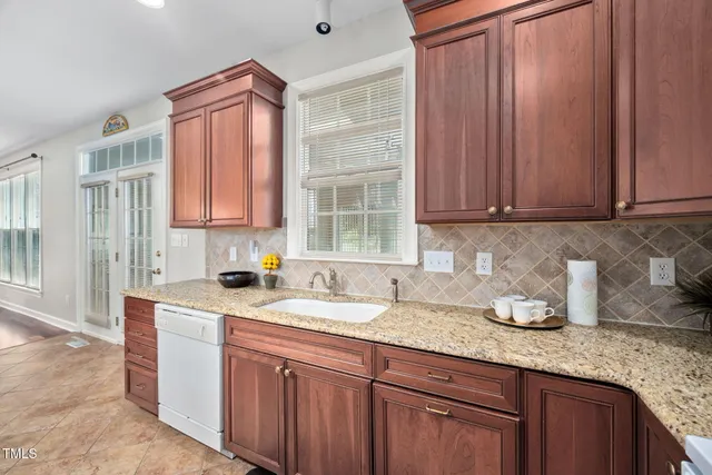 a kitchen with granite countertop a sink dishwasher stove and cabinets