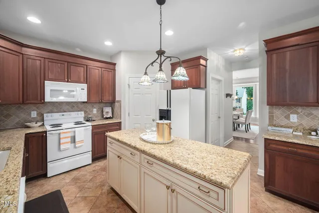 a kitchen with kitchen island granite countertop wooden cabinets and white appliances