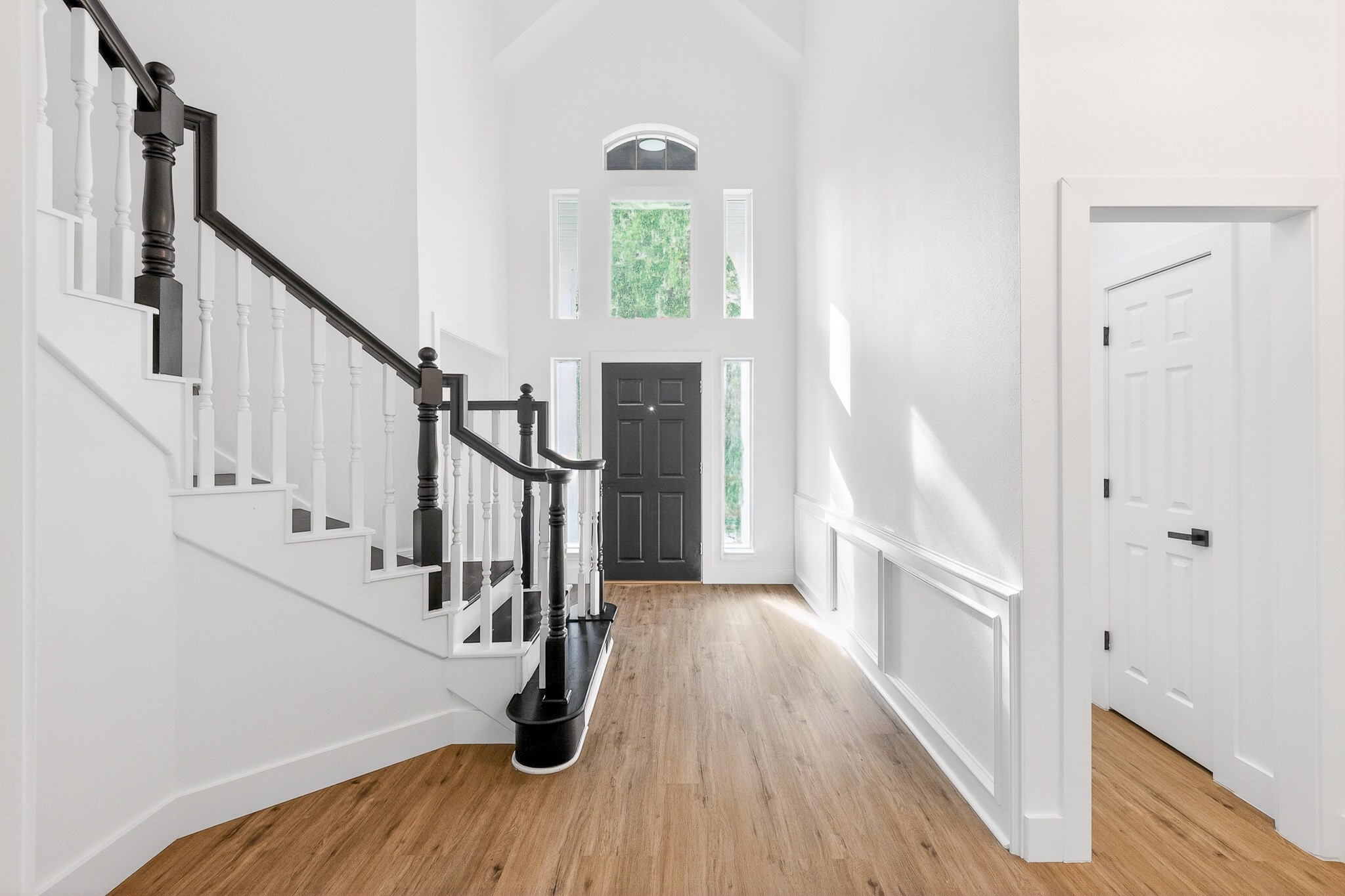 523 Rampart Lane Conroe, TX 77302 - Photo 3 of 23 Bright and inviting foyer with high ceilings, elegant staircase, and beautiful luxury vinyl flooring leading to a striking black front door.