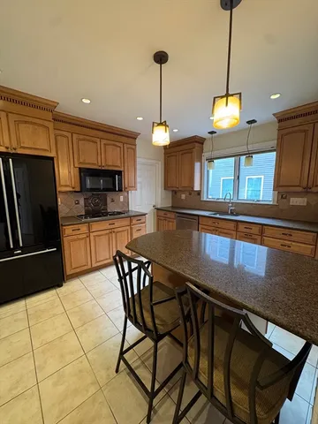 a kitchen with stainless steel appliances granite countertop a sink a stove a microwave a refrigerator with a dining table and chairs