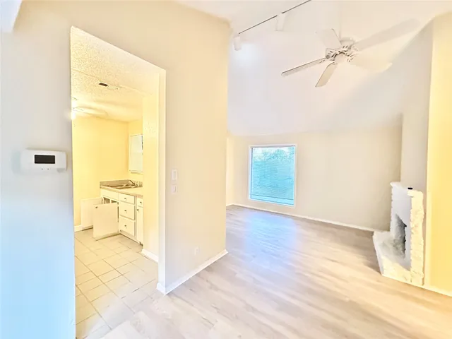 a view of a hallway with wooden floor and a bathroom