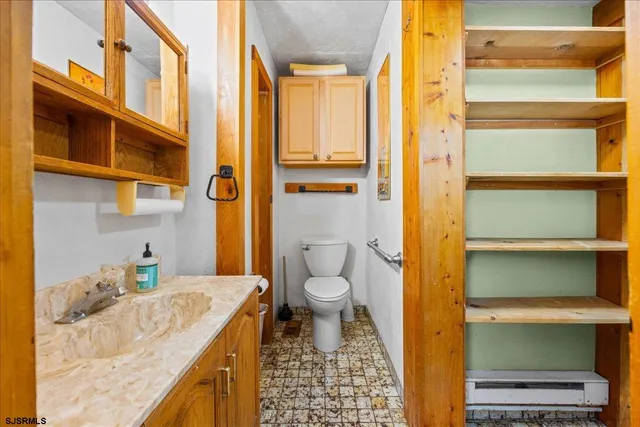 a bathroom with a granite countertop sink and a toilet