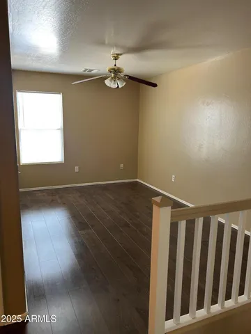 an empty room with wooden floor chandelier fan and windows