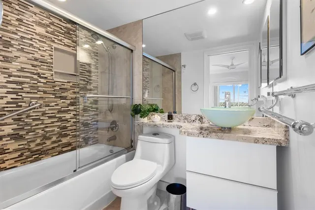 a bathroom with a granite countertop toilet sink and mirror
