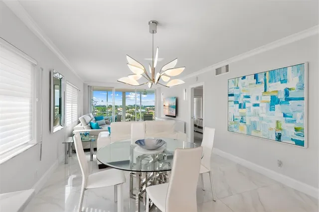 a view of a dining room with furniture a chandelier and large windows
