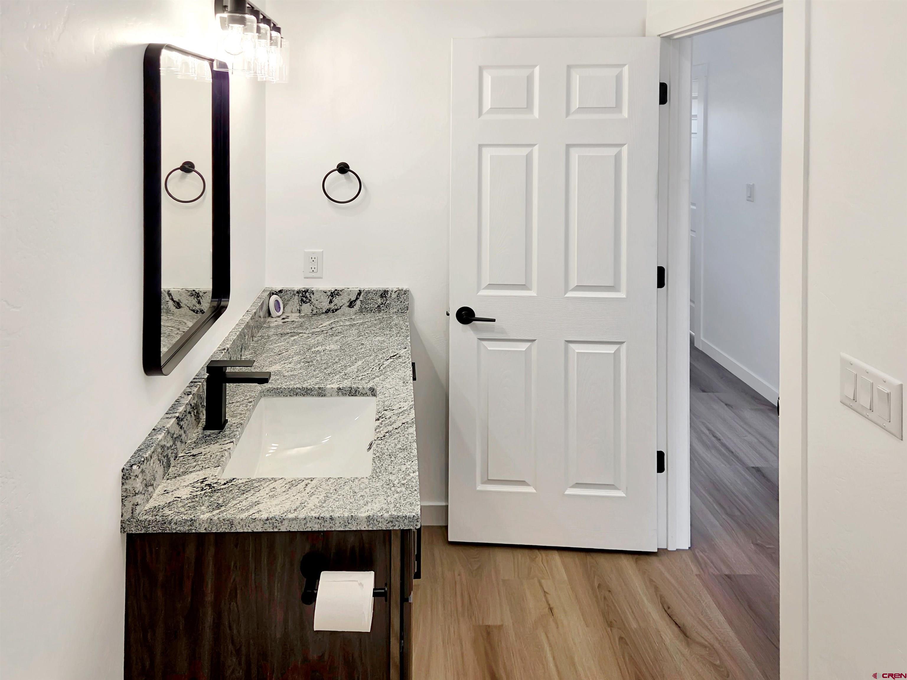 1456 Acoma Street Cortez, CO 81321 - Photo 16 of 26 a bathroom with a granite countertop sink a toilet and mirror